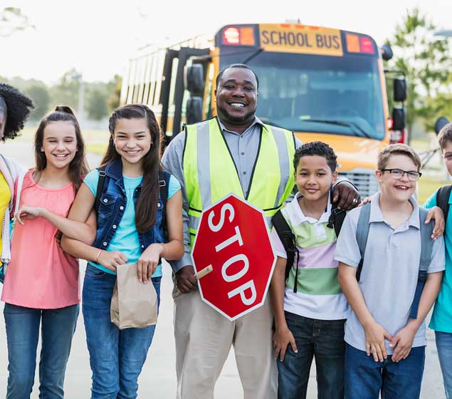School Bus Driver and Students Standing in Front of a School Bus