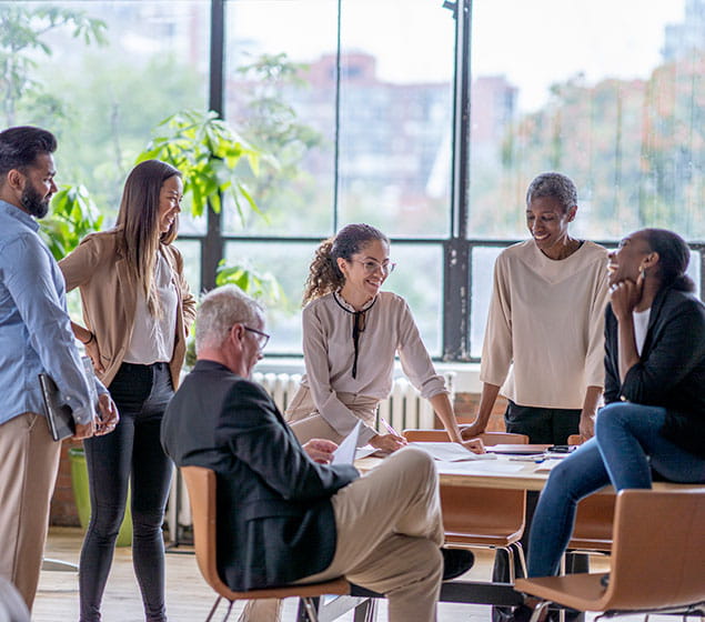 A small group of business professionals casually meet to discuss new strategies and goals for the company.