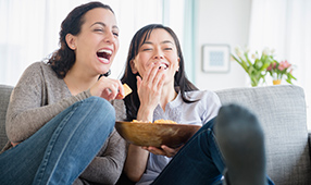 Mother and daughter eating chips and laughing