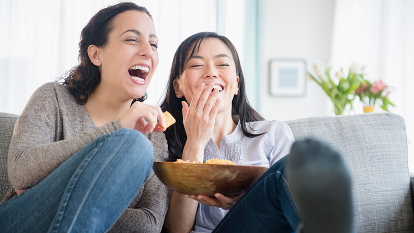 Mother and daughter eating chips and laughing
