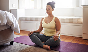 Young woman sitting on a yoga mat and meditating
