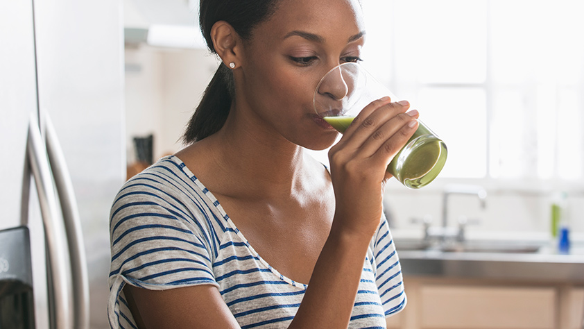Woman drinking a green breakfast smoothie