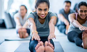 Seated young woman stretching in a group fitness class