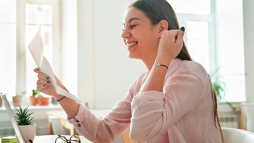 Young woman happily reading a letter that contains good news