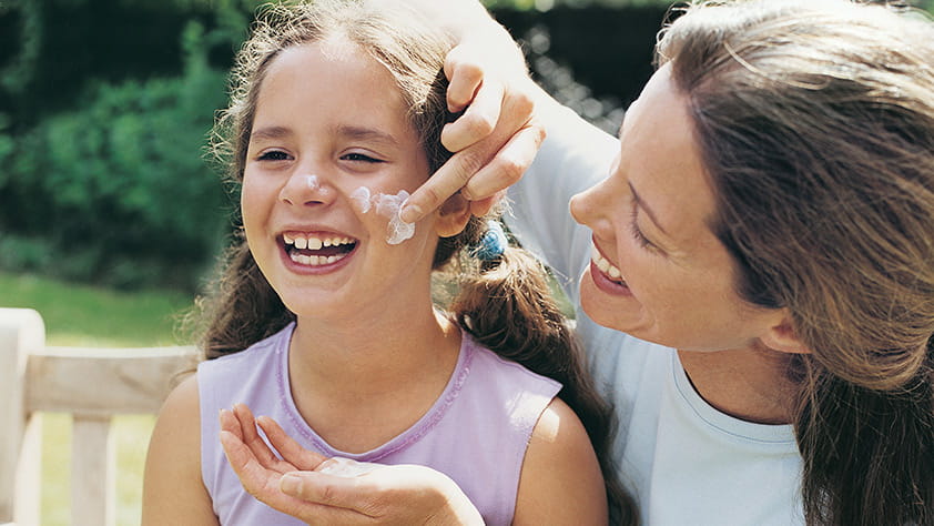 Mother applying sunscreen to her daughter's cheek