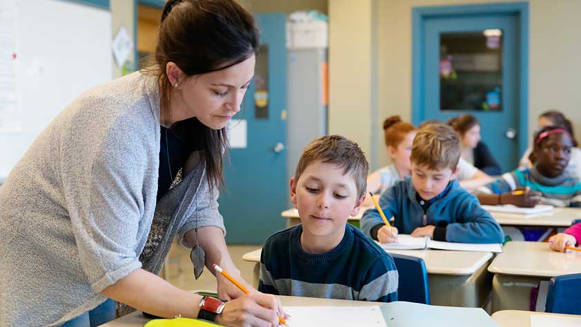 How to Cope With 7 Common Educator Health Problems - Female Teacher Helping a Young Student at His Desk
