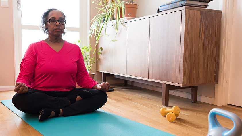 Older African-American Woman Exercising Indoors and Doing Yoga