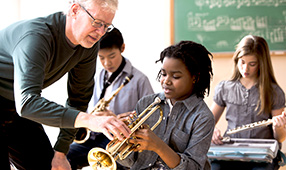 Older male teacher instructing young music students