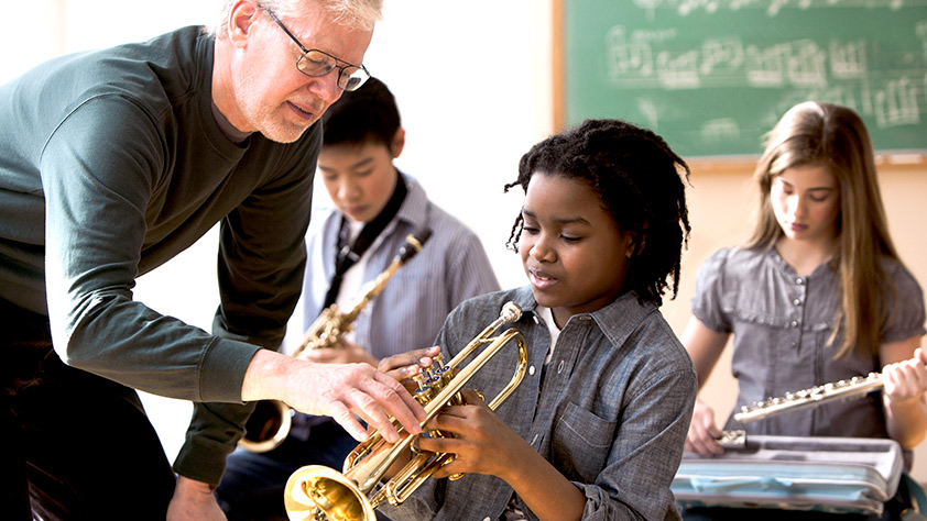 Older male teacher instructing young music students