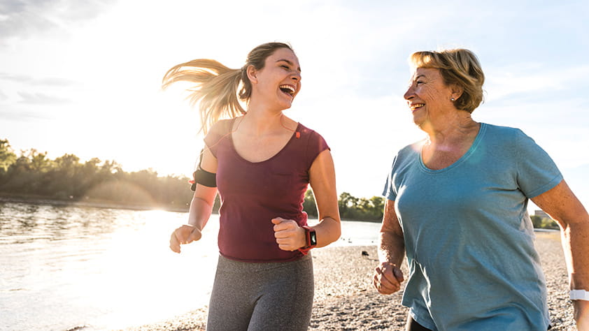 Mother and daughter having fun, jogging together along a river