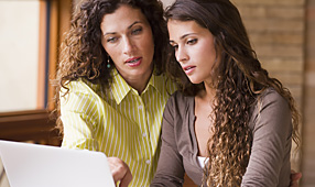 Mother and teen daughter looking at information on a laptop screen