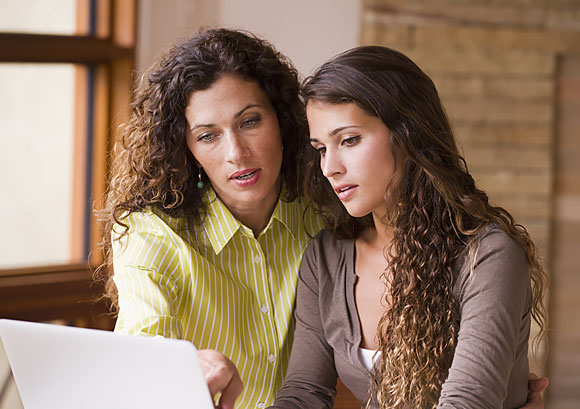 Mother and teen daughter looking at information on a laptop screen