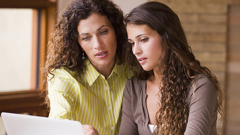 Mother and teen daughter looking at information on a laptop screen