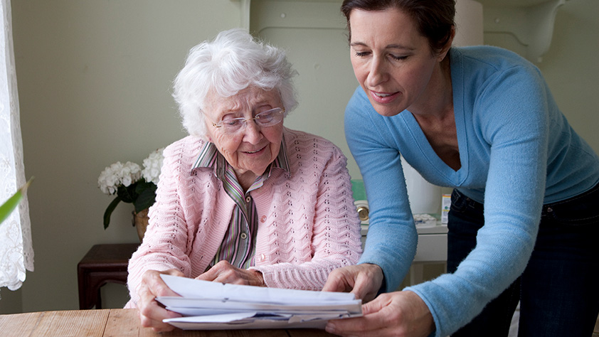 Elderly Woman Being Assisted with Paperwork
