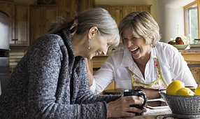 Senior Women Laughing and Drinking Coffee at Dining Table