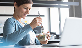 Woman eating lunch in front of her laptop