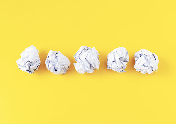 5 Money Mistakes Educators Need to Avoid - photo of five crumpled sheets of paper on yellow background