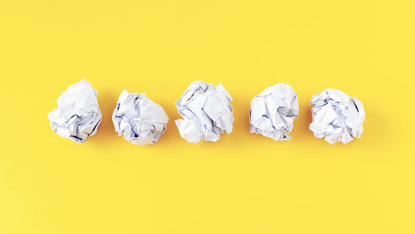 5 Money Mistakes Educators Need to Avoid - photo of five crumpled sheets of paper on yellow background