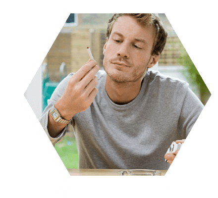 Man sitting at table looking at a cigarette he is holding