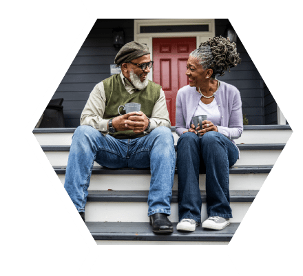 Older man and woman sitting on house steps smiling at each other