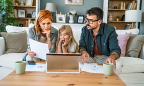 Young family sitting on the couch reviewing NEA life and disability insurance options