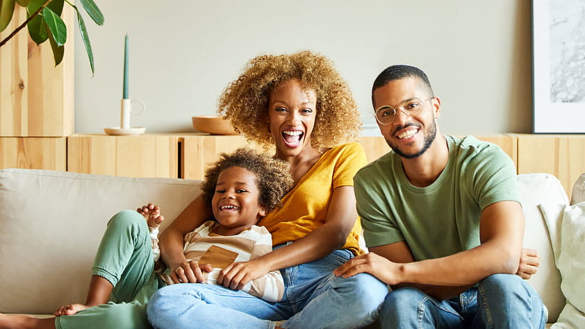 A family sitting together on their living room sofa, illustrating the everyday moments insurance can help protect.