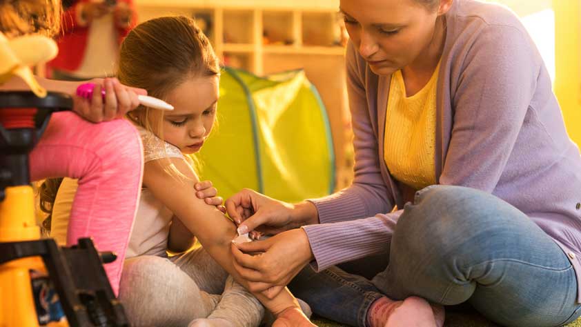 Woman Putting Adhesive Bandage on a Little Girl's Elbow