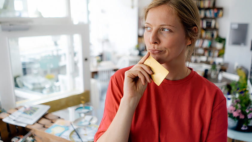 Credit Card Myths - Woman Holding a Credit Card and Thinking