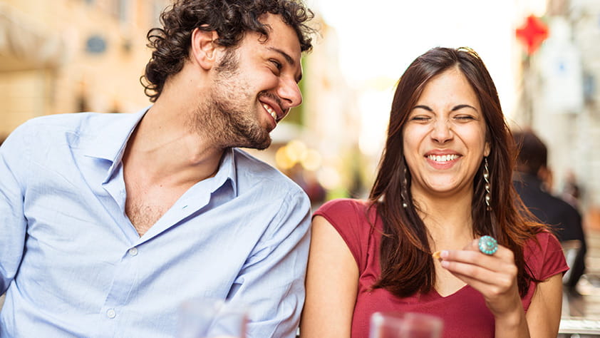 Happy couple laughing and eating outside at a restaurant