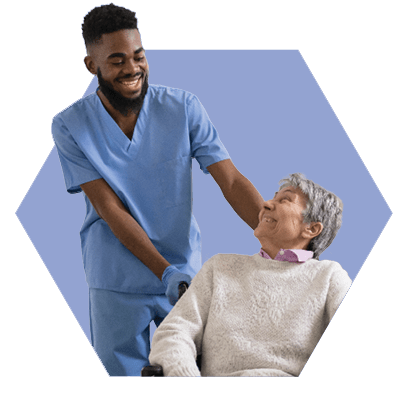 Man in a Wheelchair Assisted by a Caregiver in Scrubs