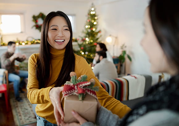 Young woman handing a holiday present to a friend