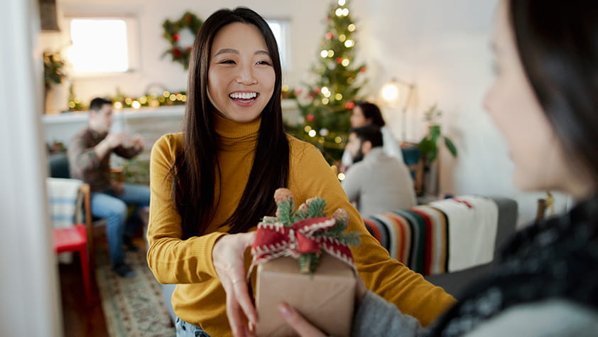 Young woman handing a holiday present to a friend
