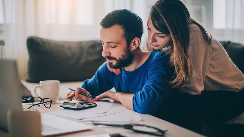 7 Steps to Getting Your Finances Under Control - Couple Going Over Finances Using a Calculator and Laptop