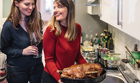 Two Female Friends Admiring Turkey Pulled Out of Oven