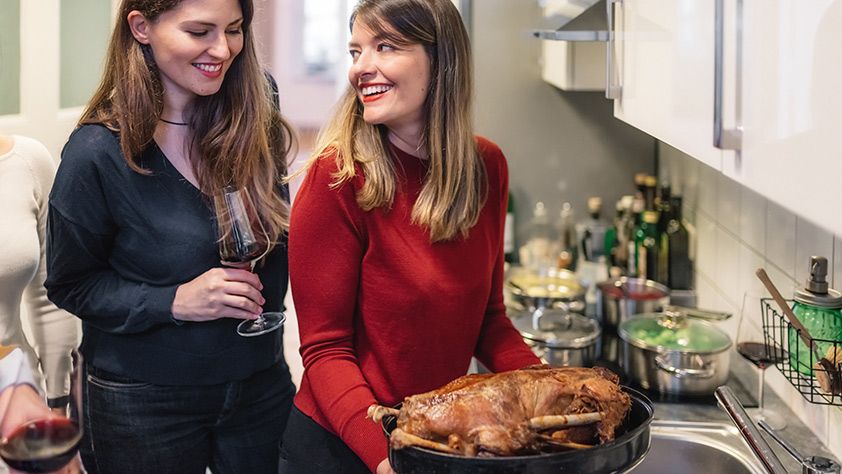 Two Female Friends Admiring Turkey Pulled Out of Oven