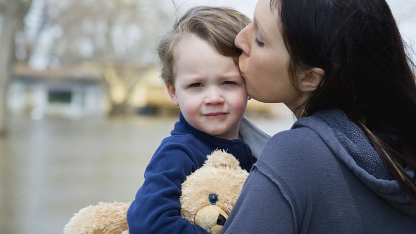 Mother Carrying Son and Standing in Flooded Town - How to Prepare for and Recover From a Natural Disaster
