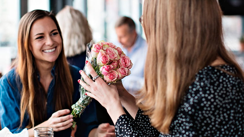 Woman Receiving Bouquet of Flowers from Female Friend