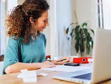 Woman Working on Finances with Calculator and Laptop
