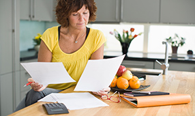 Middle Aged Woman Reviewing Finances in Kitchen