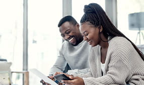 Shot of a young couple going through the steps to secure an NEA Personal Loan on their laptop at home