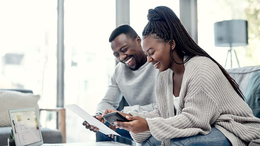 Shot of a young couple going through the steps to secure an NEA Personal Loan on their laptop at home