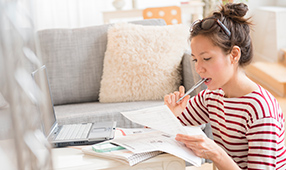 Woman Biting Pen While Reviewing Financial Statement