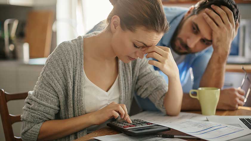 The Surprising Truths About Payday Loans - Concerned Couple Looking Through Paperwork and Using a Calculator