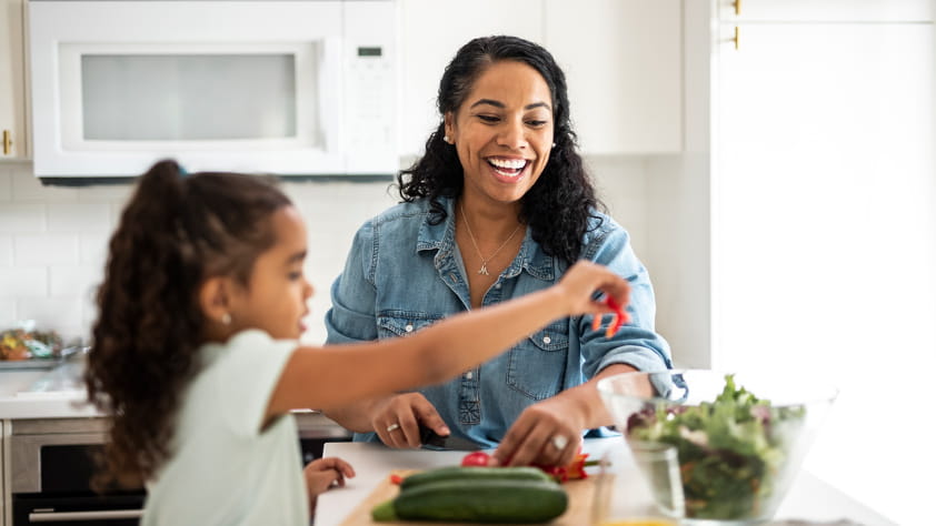 Mother and daughter preparing vegetables for lunch in the kitchen
