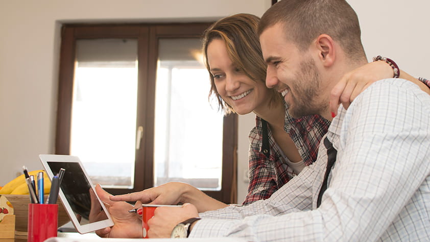 Couple Smiling Looking at Tablet