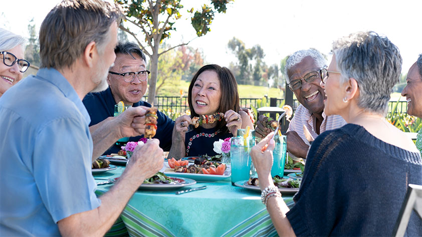 Happy gathering of senior friends dining outside