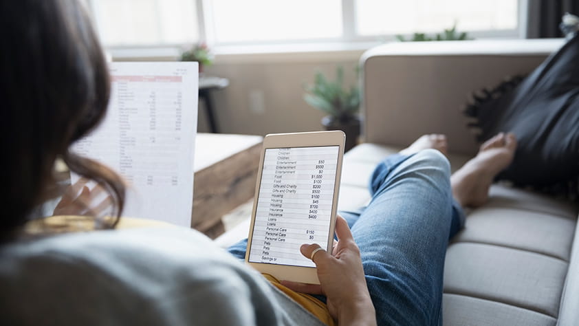 Woman Sitting on Couch Reviewing Tablet
