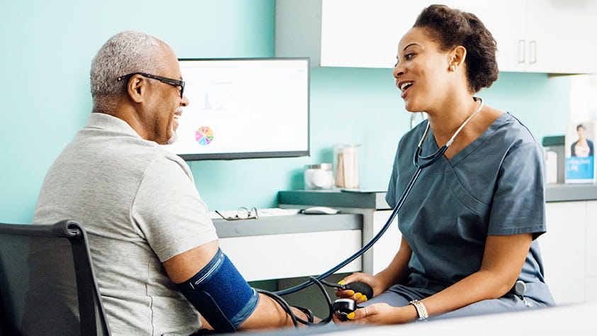 Happy female doctor checking an older male patient's blood pressure