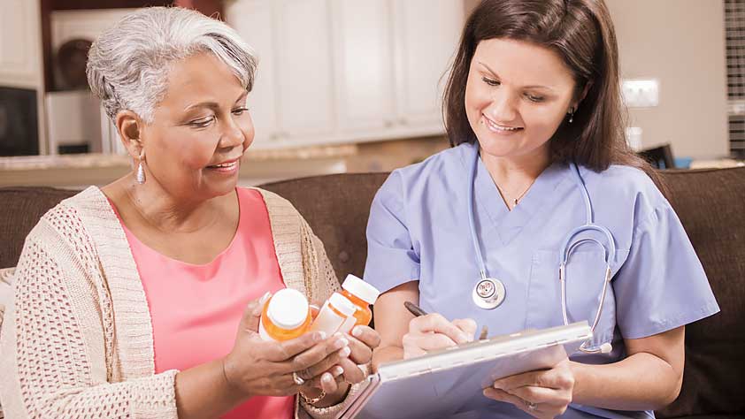 Home Healthcare Nurse Explains Medications to Senior Adult Woman
