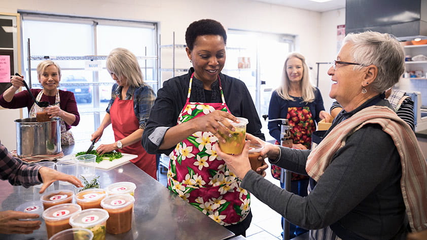 Volunteers packaging soup containers in a soup kitchen